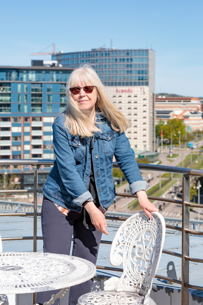 Bilden visar Eva-Lena som drar ut en stol på kontorshotellets takterrass nära Korsvägen i Göteborg.